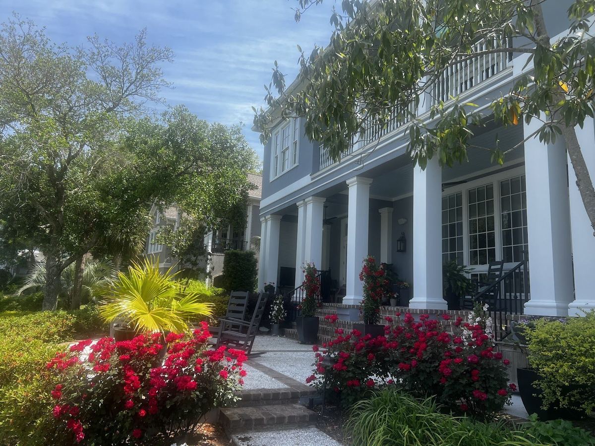 Red blooming azaleas and shrubs along the front porch of a home, landscaped by Prestige Landscaping