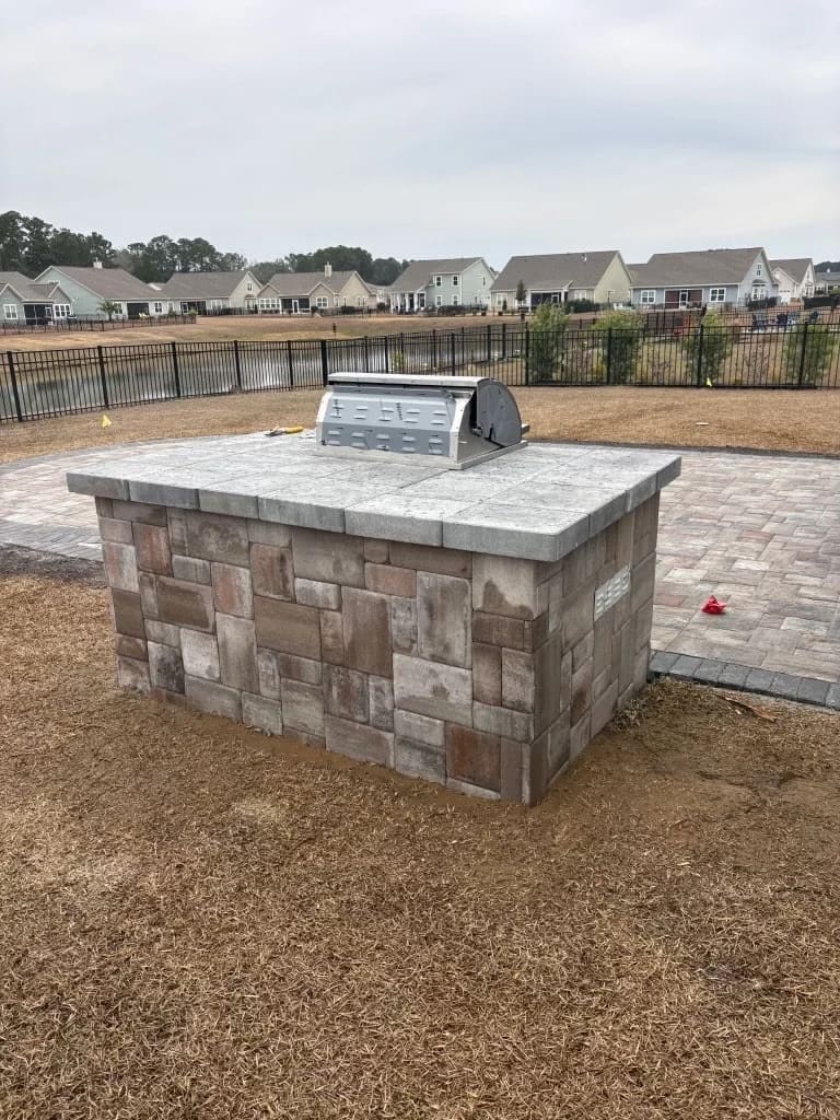 Stone outdoor kitchen island with grill on a new paver patio