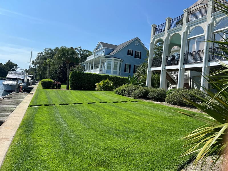 Freshly mowed lawn beside waterfront homes and a dock
