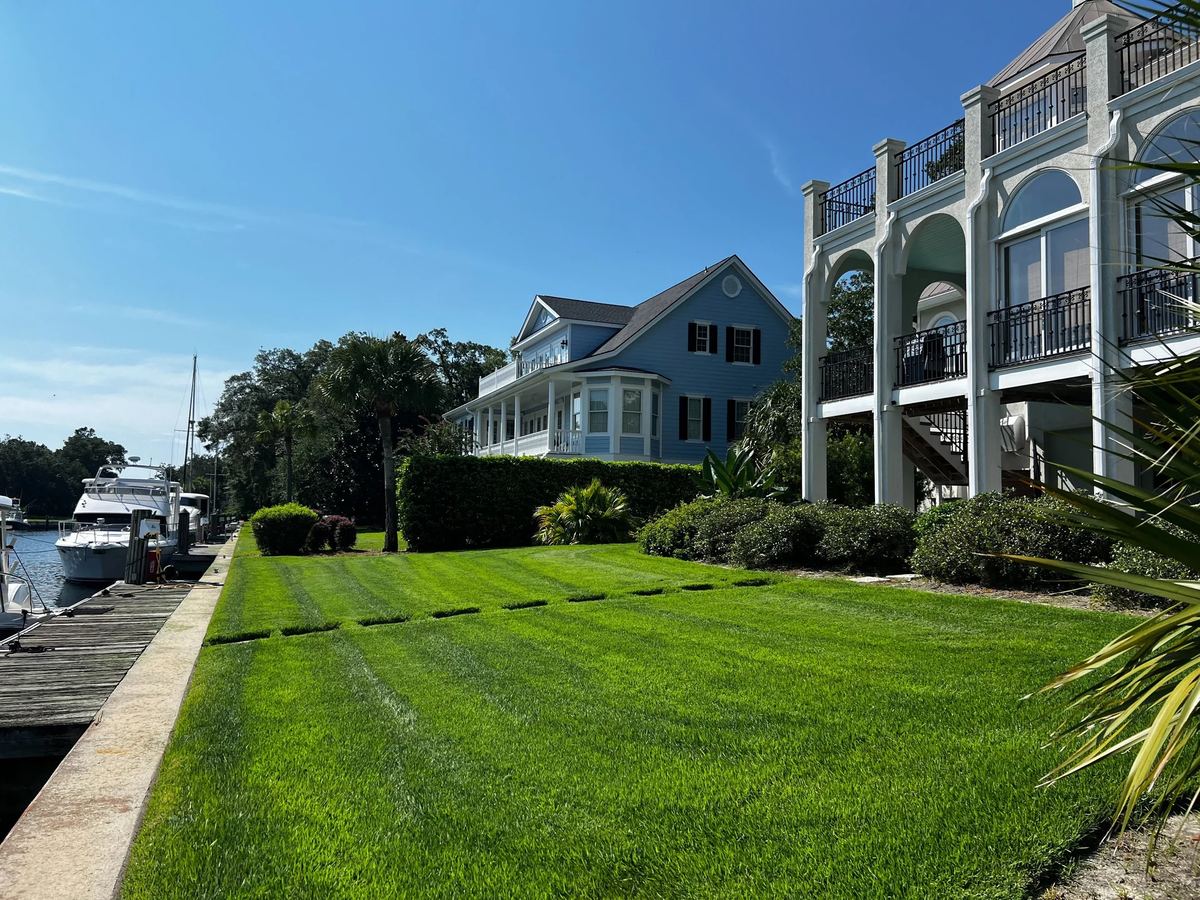 Striped green lawn beside waterfront homes